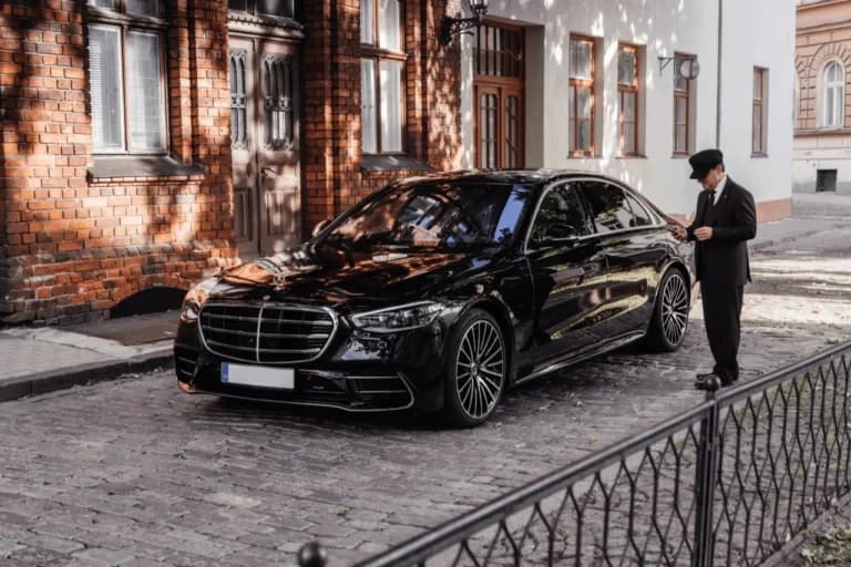 Professional chauffeur beside a black Mercedes-Benz S-Class on a Barcelona street